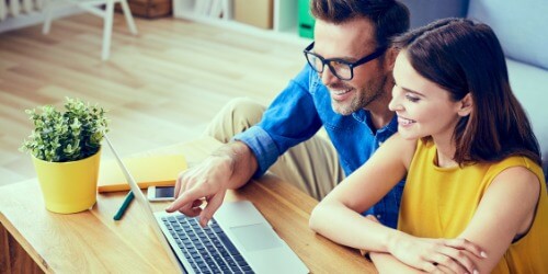 Mann und Frau arbeiten gemeinsam an einem Laptop am Tisch